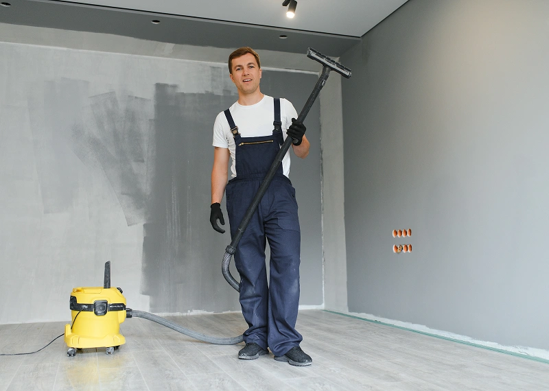 Man in overalls holding vacuum cleaner