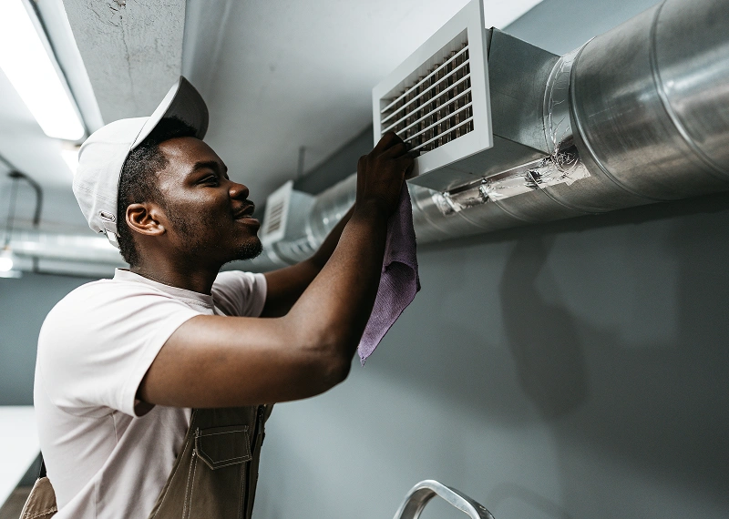 Technician cleaning air vent with cloth