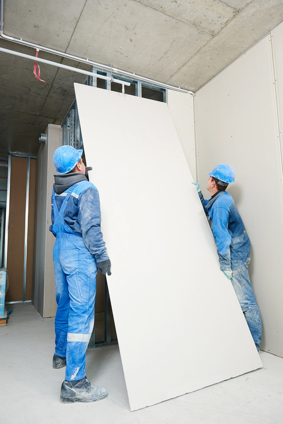 Workers placing drywall in a building