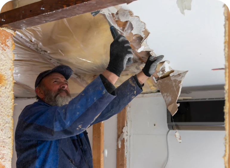 Man removing ceiling drywall with gloves